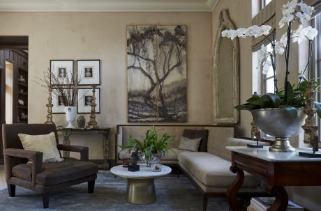 Cozy living room with elegant furnishings, artwork, and potted plants, creating a warm ambiance.