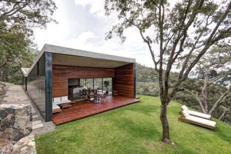 Modern wood-and-steel structure with large glass windows overlooking lush greenery.