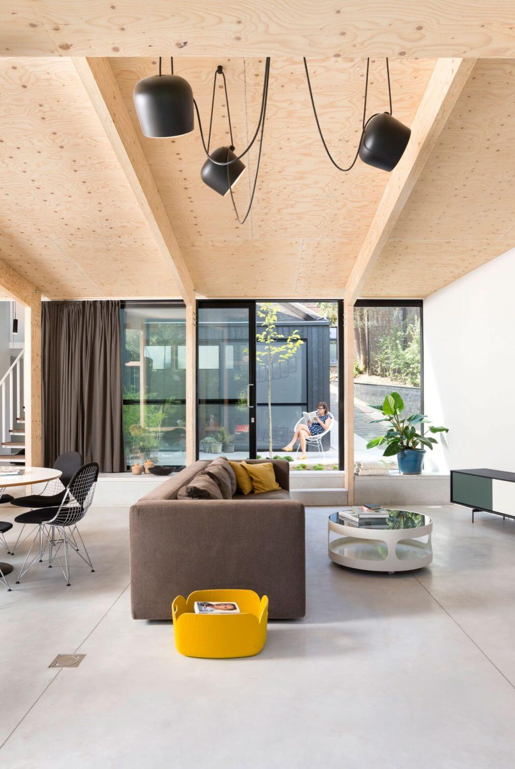 Modern open-concept living space with wooden ceilings, pendant lighting, and minimalist furnishings.