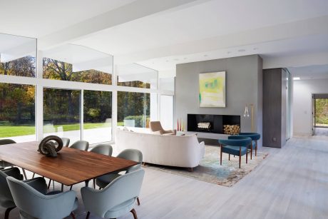 Spacious open-plan living room with floor-to-ceiling windows, modern furniture, and a fireplace.