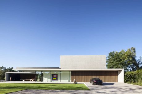 Modern minimalist house with sleek exterior, large glass windows, and ample lawn space.