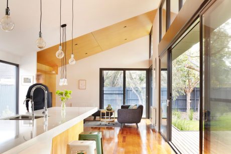 Spacious and bright open-plan kitchen and living area with modern lighting and wood accents.