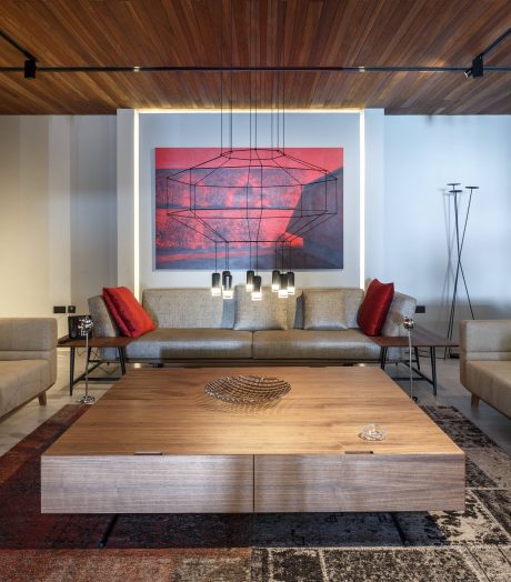 A modern living room with a geometric light fixture, warm wood tones, and a large abstract painting.