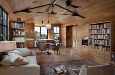 Cozy cabin interior with wood-paneled ceiling, built-in bookshelves, and rustic decor.