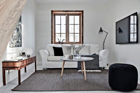 Cozy living room with wooden window frames, sleek white sofa, and modern decor touches.