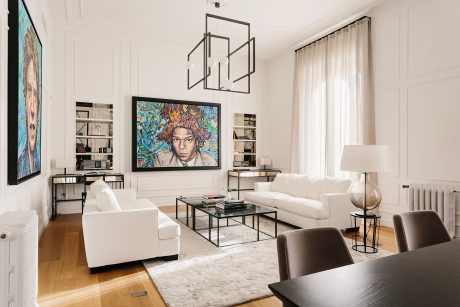 Elegant modern living room with minimalist furnishings, ornate artwork, and geometric lighting.