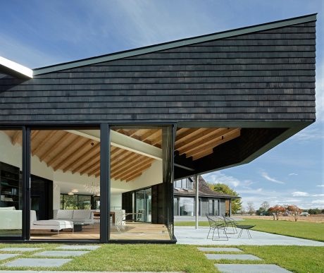 Sleek modern architecture with wooden beams, slate siding, and expansive glass patio doors.