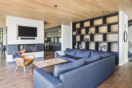Large open-concept living room with wooden ceiling, built-in shelving, and modern furniture.