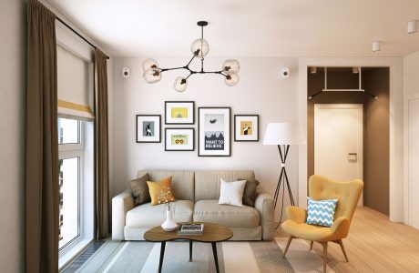 Modern living room with neutral sofa, pendant lighting, framed wall art, and yellow accent chair.