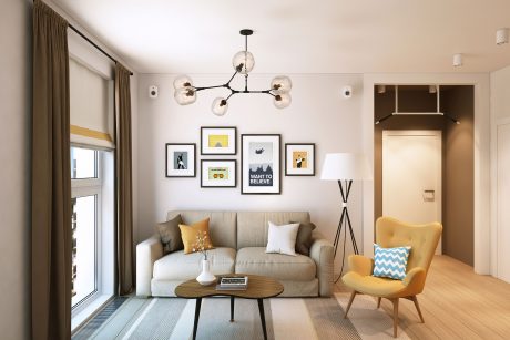 Modern living room with neutral sofa, pendant lighting, framed wall art, and yellow accent chair.