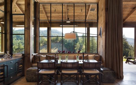 Rustic cabin interior with large windows, wood beams, and contemporary furniture.