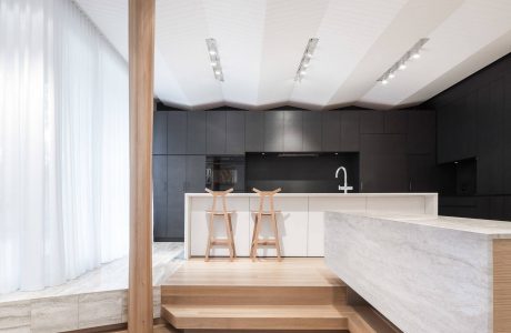 Contemporary kitchen design with sleek black cabinetry, marble countertops, and wooden accents.