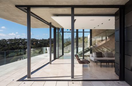 Minimalist, open-concept interior with expansive glass walls and concrete elements.