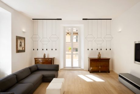 Minimalist living room with geometric pendant lights, wooden furniture, and large window.