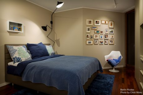 A cozy bedroom with a gallery wall, textured bedding, and a modern swivel chair.