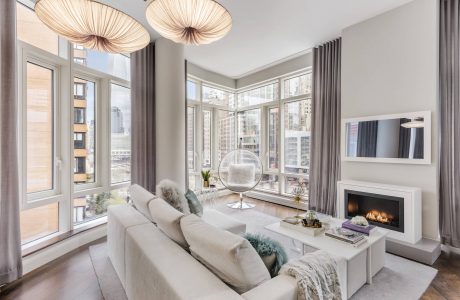 Cozy urban living space with large windows, hanging globe lamps, and a fireplace.