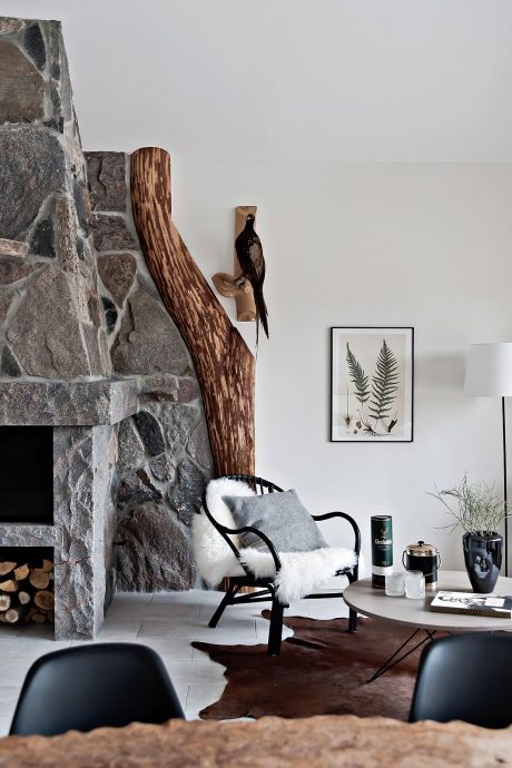 Cozy living room with stone fireplace, rustic wooden decor, and nature-inspired artwork.