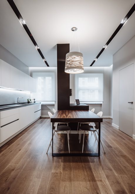 Modern, minimalist kitchen with dark wood dining table, pendant light, and sleek cabinetry.