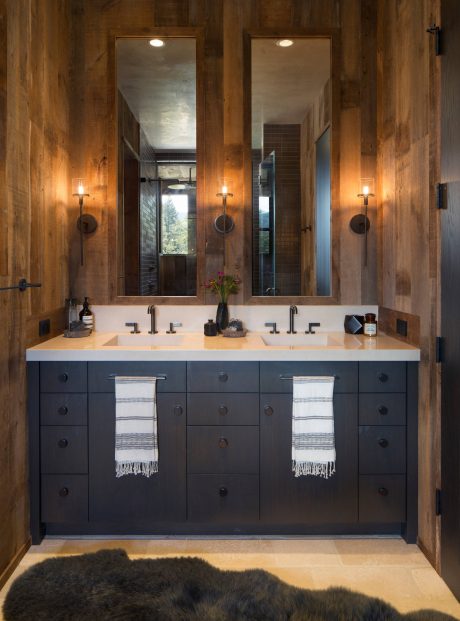 Rustic wooden walls, dual vanity sinks, and mirrors in a cozy bathroom design.
