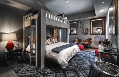 A stylish modern bedroom with a wooden bunk bed, patterned rug, and industrial accents.