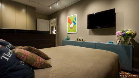 Elegant modern bedroom with sleek cabinets, artwork, and a large flat-screen TV.