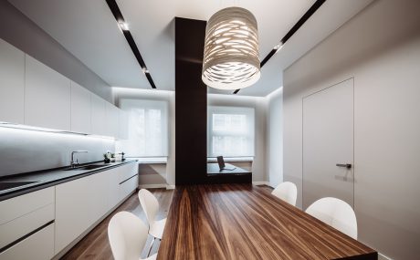 Sleek modern kitchen with minimalist cabinets, wooden dining table, and sculptural lighting.
