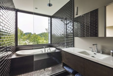 Luxurious modern bathroom with black brick walls, freestanding tub, and vanity.