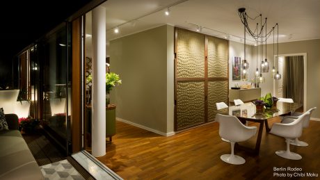 Spacious open-plan living area with textured wall panels, modern lighting, and hardwood flooring.