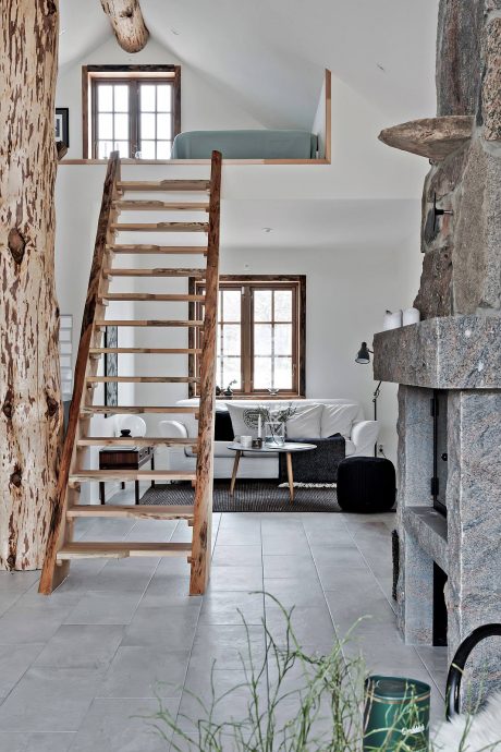 Rustic loft with wooden staircase, cozy living area, and stone fireplace accents.