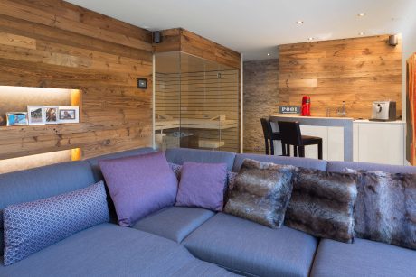 Warm, rustic interior with wood walls, plush sofa, and modern kitchen appliances.