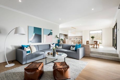 Spacious and inviting living room with modern furniture, abstract art, and an open kitchen.