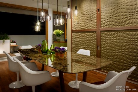 Sleek modern dining area with geometric wall paneling and pendant lighting.