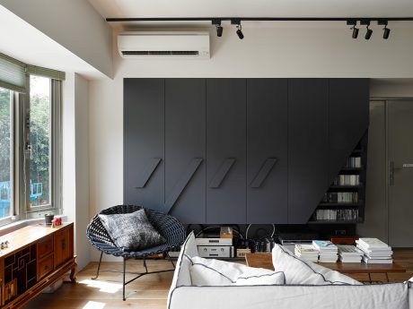 A modern living room with black cabinetry, a cozy lounge chair, and a window with natural light.