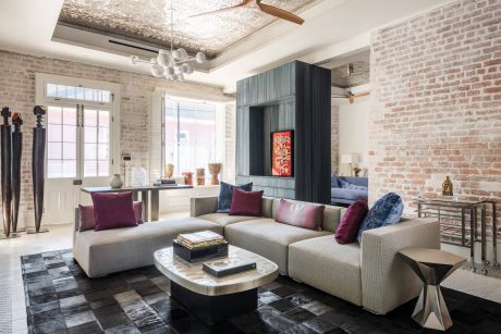 Spacious modern living room with exposed brick walls, neutral-toned sofa, and decorative lighting.