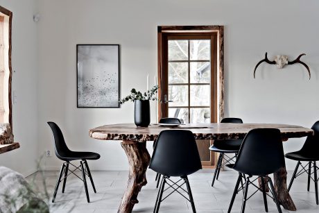 A rustic wooden dining table with black chairs, framed artwork, and natural accents create a modern, minimalist aesthetic.