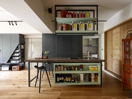 Contemporary kitchen with sleek open shelving, rustic wood flooring, and industrial-style furniture.