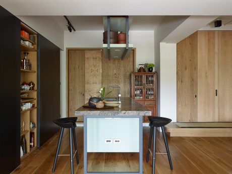 Modern kitchen with wooden cabinetry, marble countertops, and a minimalist central island. Sleek appliances and decor.
