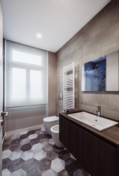 Sleek modern bathroom with hexagonal tile flooring, vanity, and large window.