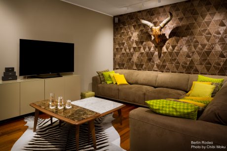 Cozy living room with a modern tile wall, plush brown sofa, and wooden coffee table.