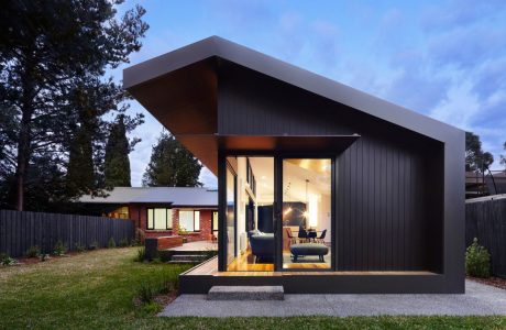 A modern, angular cabin-style home with large windows and a cozy, inviting interior.