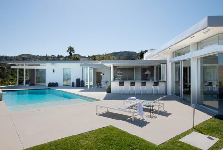 Sleek, modern architecture with a pool, patio, and bar area overlooking hills.