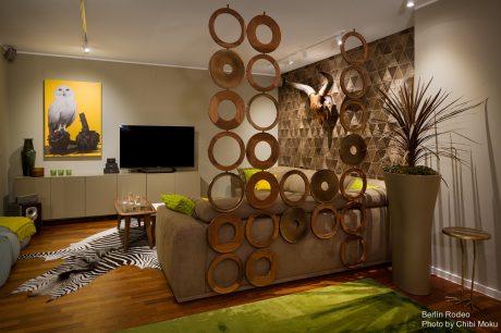 Eclectic living room with wooden ring wall decor, zebra print rug, and statement plant.