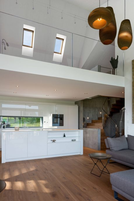 Modern open-concept kitchen with high ceilings, pendant lights, and minimalist decor.