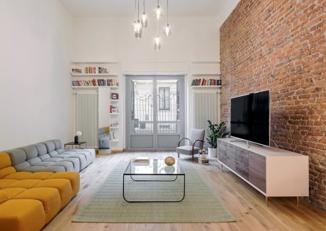 Bright, open-plan living space with exposed brick wall, built-in shelves, and modern furnishings.