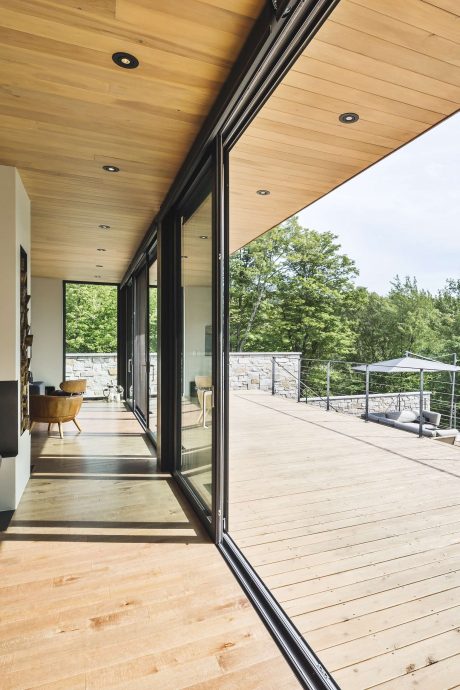 Spacious modern interior with large glass windows overlooking a wooded landscape.