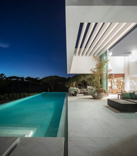 Sleek modern architecture with a turquoise pool and verdant landscaping.