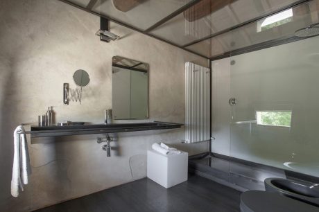 Minimalist bathroom with concrete walls, modern fixtures, and sleek vanity.