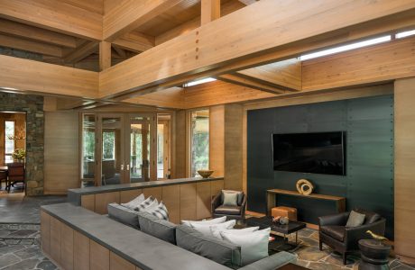 Spacious wooden-beam interior with stone flooring, built-in cabinetry, and large TV.