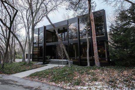 A sleek, modern glass and concrete building nestled among bare-branched trees.