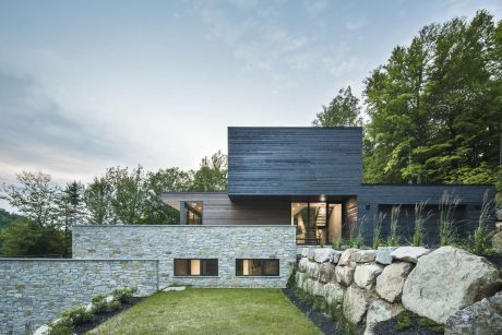 A modern, two-story home with a stone exterior, wooden accents, and large windows.